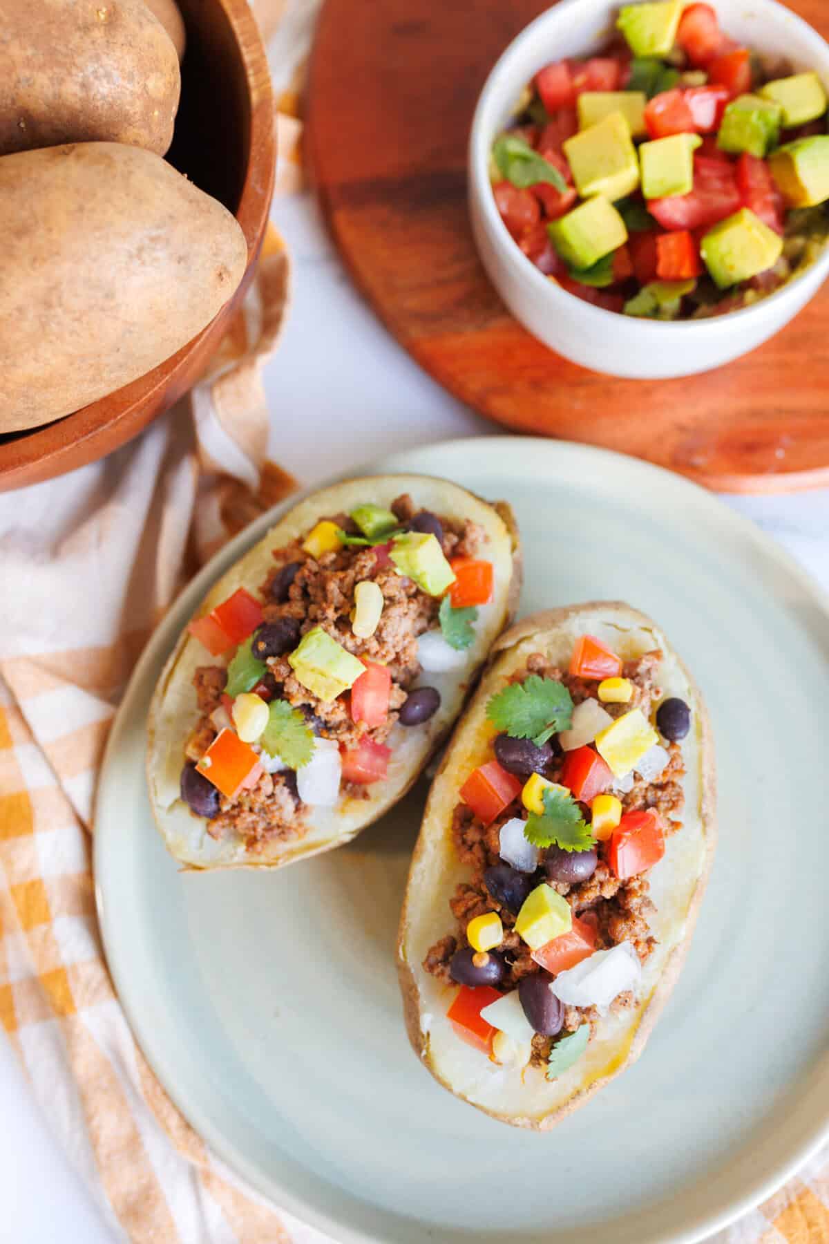 Stuffed Taco Potatoes Close-up of taco stuffed baked potatoes filled with seasoned meat, black beans, corn, diced vegetables, and fresh cilantro.