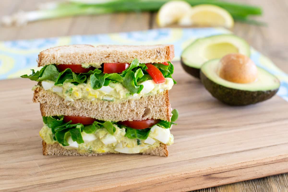 avocado egg salad sandwich on cutting board. 