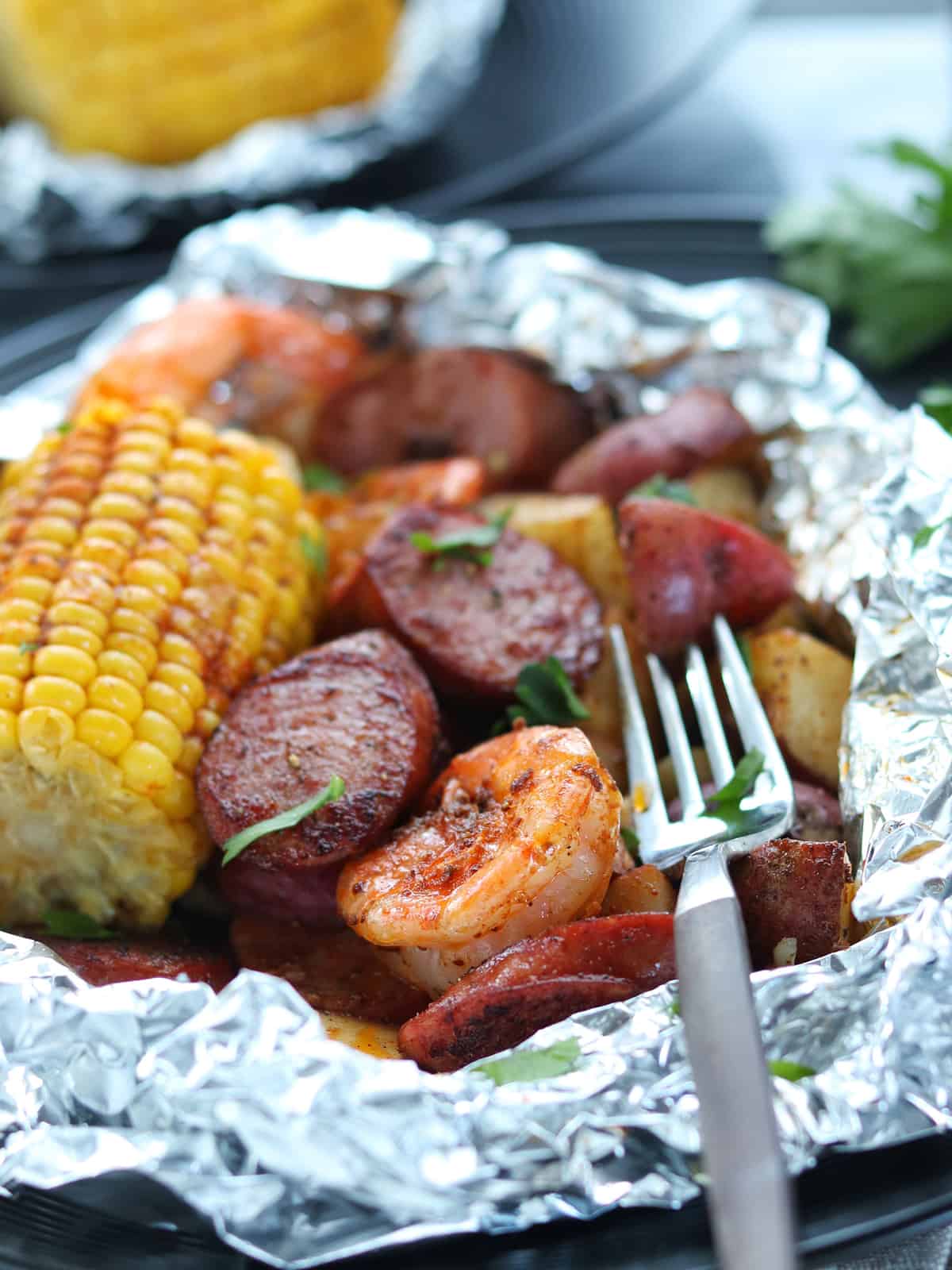 Close up shot of shrimp boil foil packets with fork