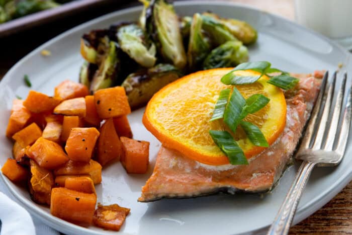 Salmon with roasted vegetables, garnished with green onions.