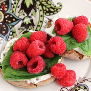English muffins topped with cream cheese, fresh basil and raspberries.