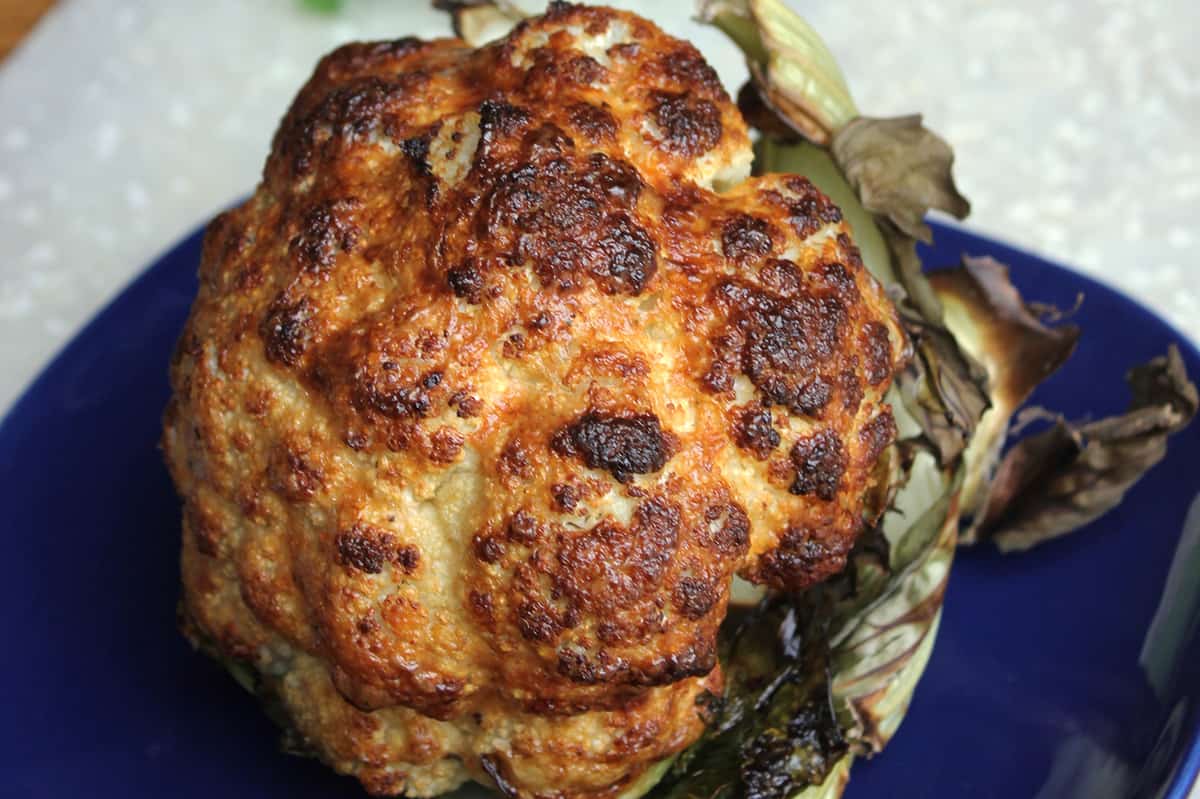 whole roasted cauliflower on blue plate