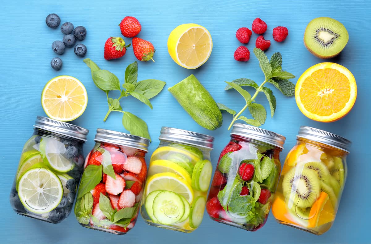 masos jars filled with water and various fruits on blue background