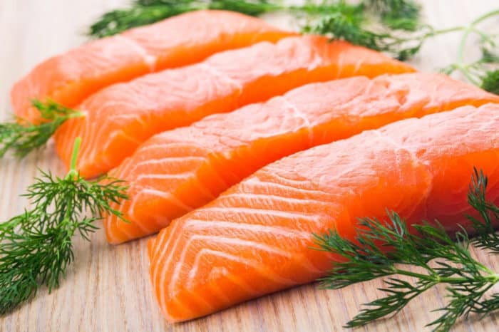 4 salmon filets lined up with fresh herbs