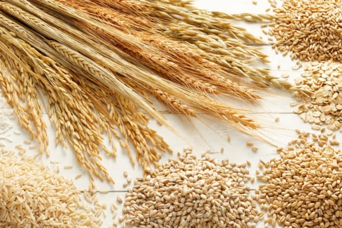 Wheat and other whole grains on wood background