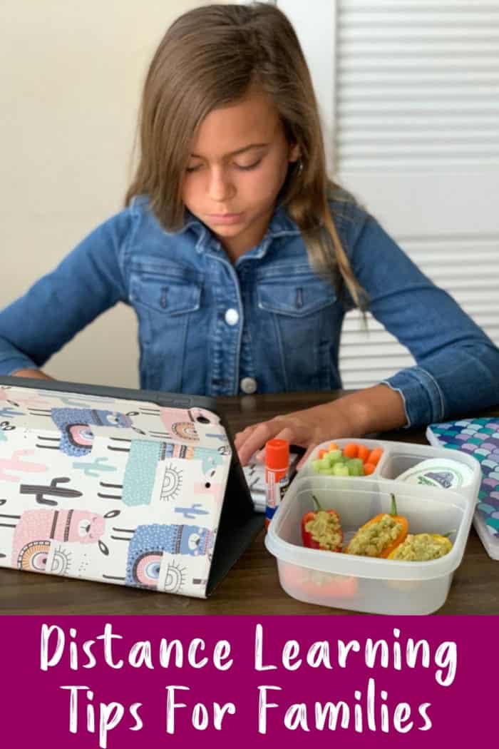 Girl sitting at table with lunchbox and iPad