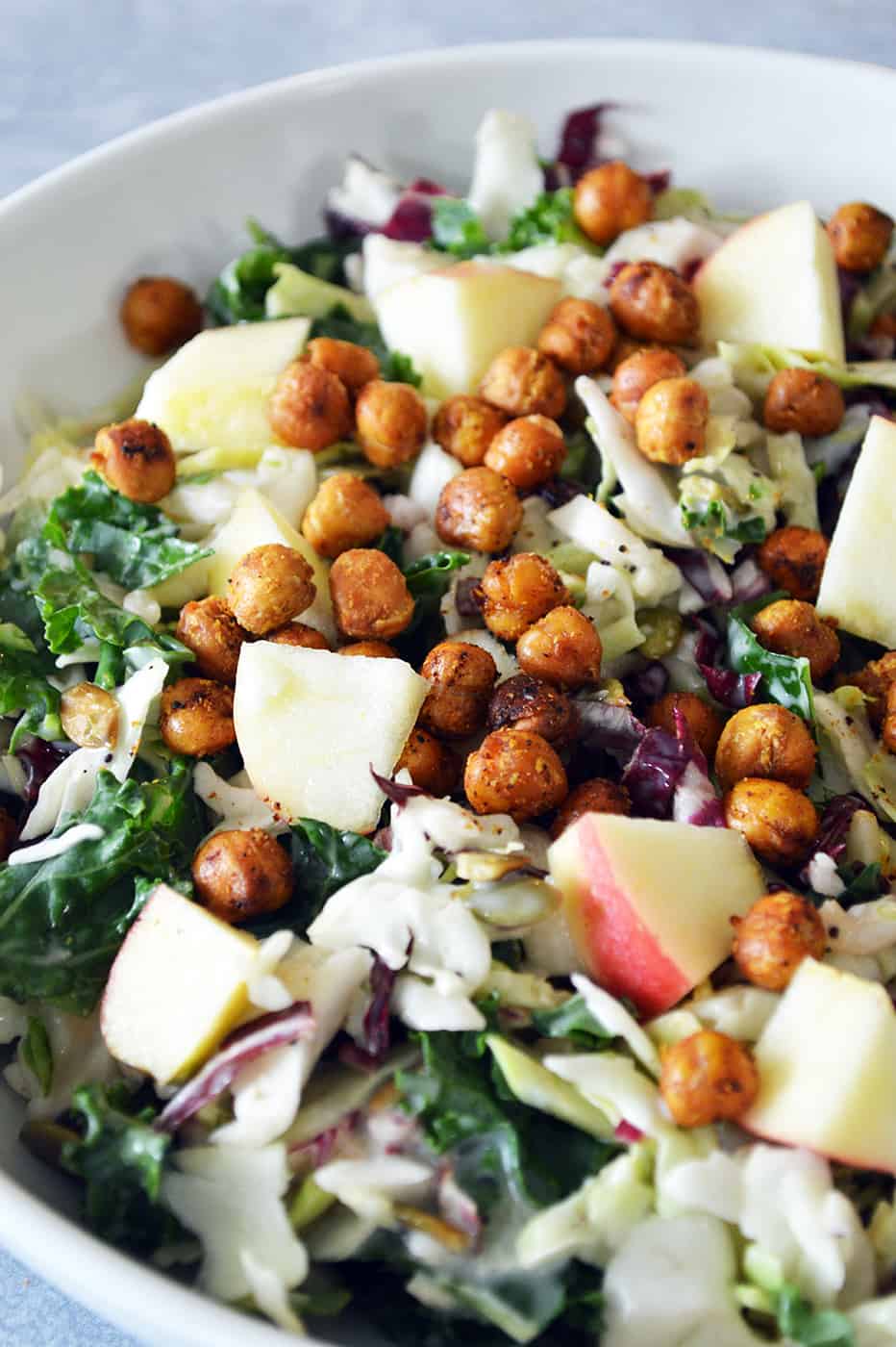 Close up of bowl of salad topped with roasted chickpeas and apples