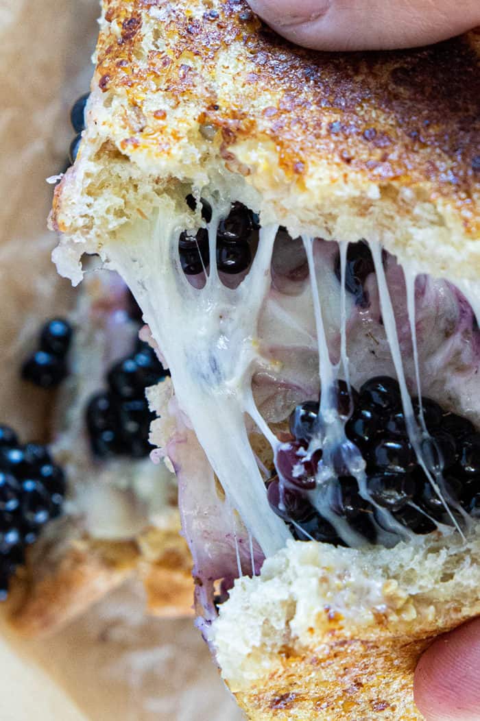 Grilled cheese cut in half with ooey-gooey cheese and blackberries