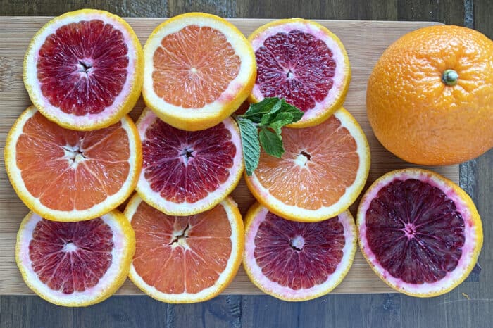 Slices of blood oranges and cara cara oranges on cutting board.