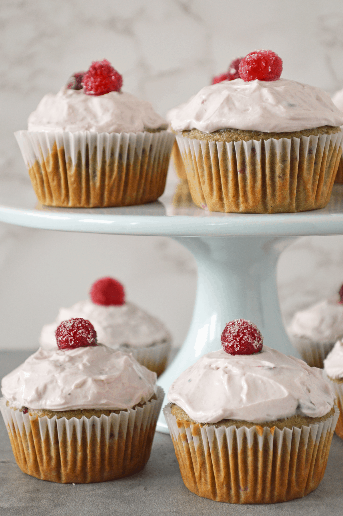 Cranberry cupcakes on cake stand with cupcakes underneath.