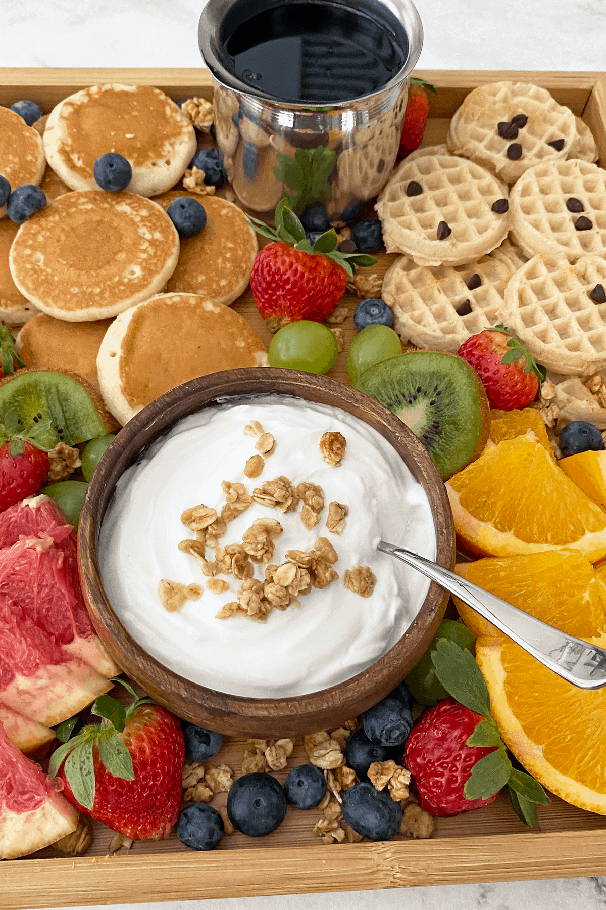 Close up of breakfast grazing board focusing on yogurt topped with granola.