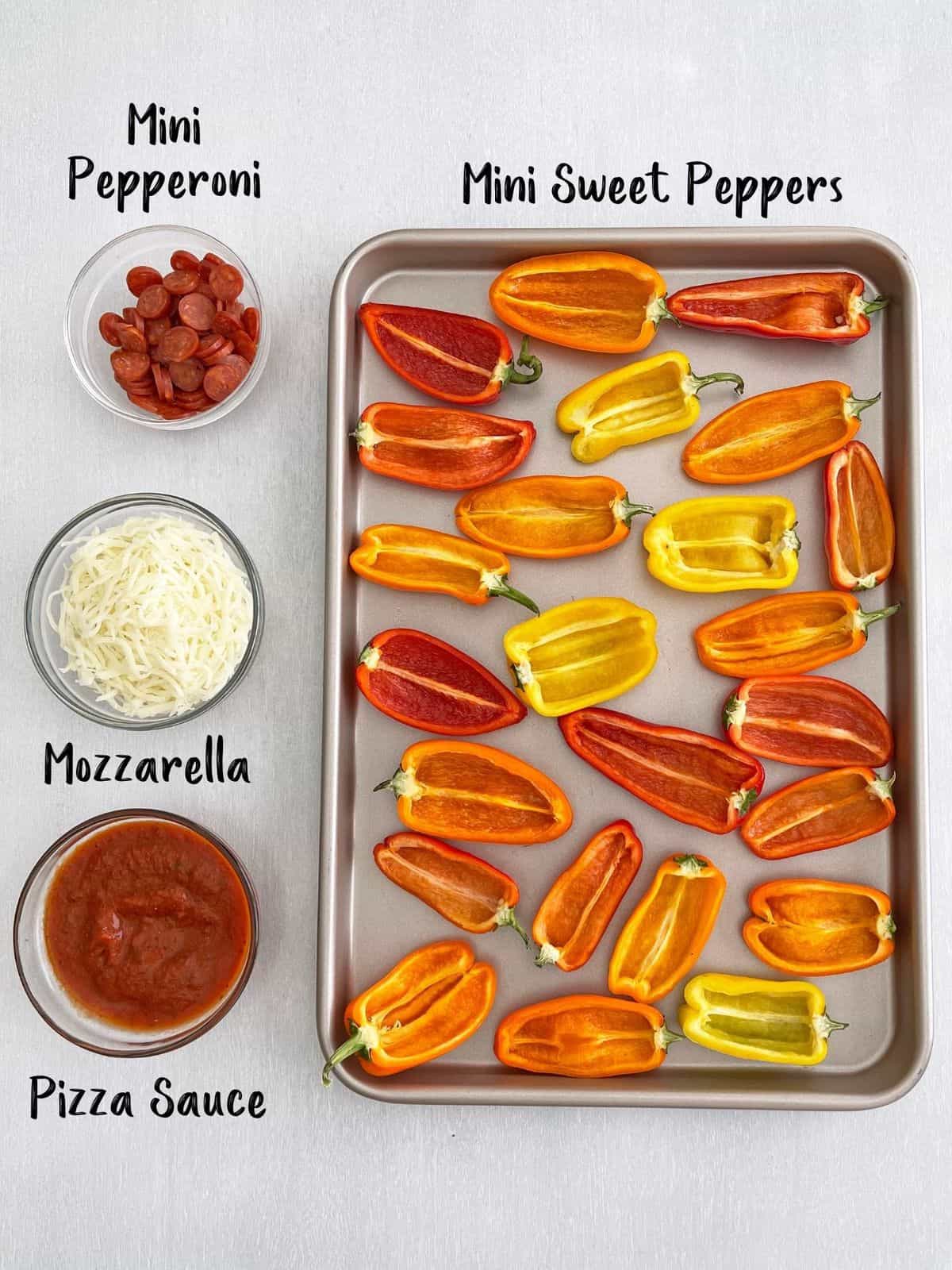 Mini sweet peppers on baking sheet with bowls of toppings on the side.