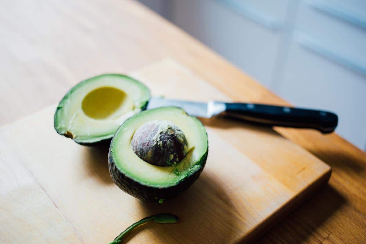 Avocado on cutting board with knife.