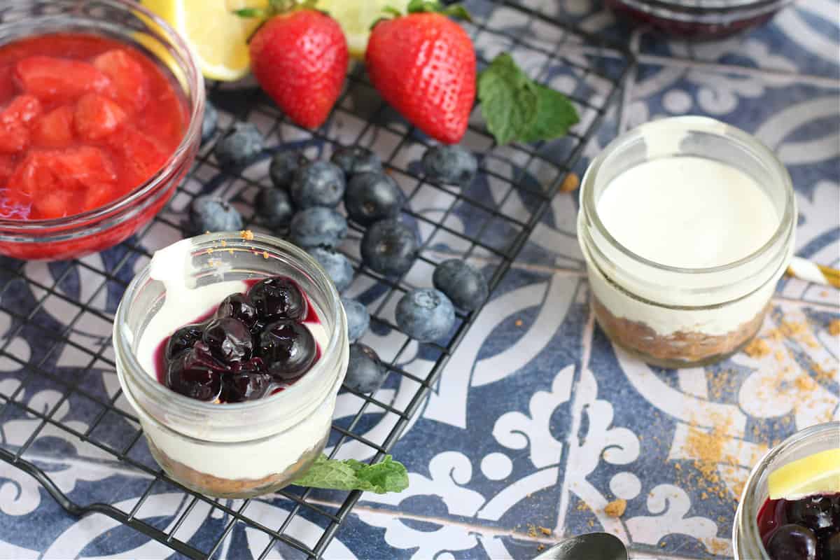 Healthy No Bake Cheesecakes in mason jars with fruit topping