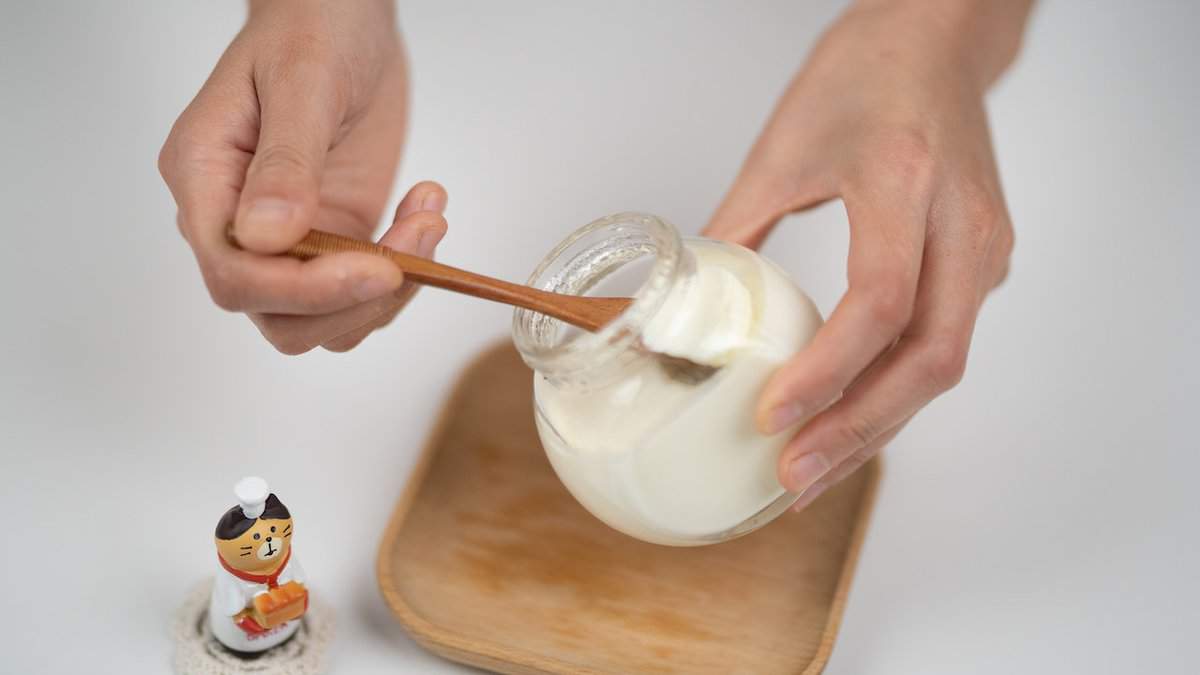 Coconut Granola Fruit Cups - Scooping Yogurt in Glass Jar with Wooden Spoon