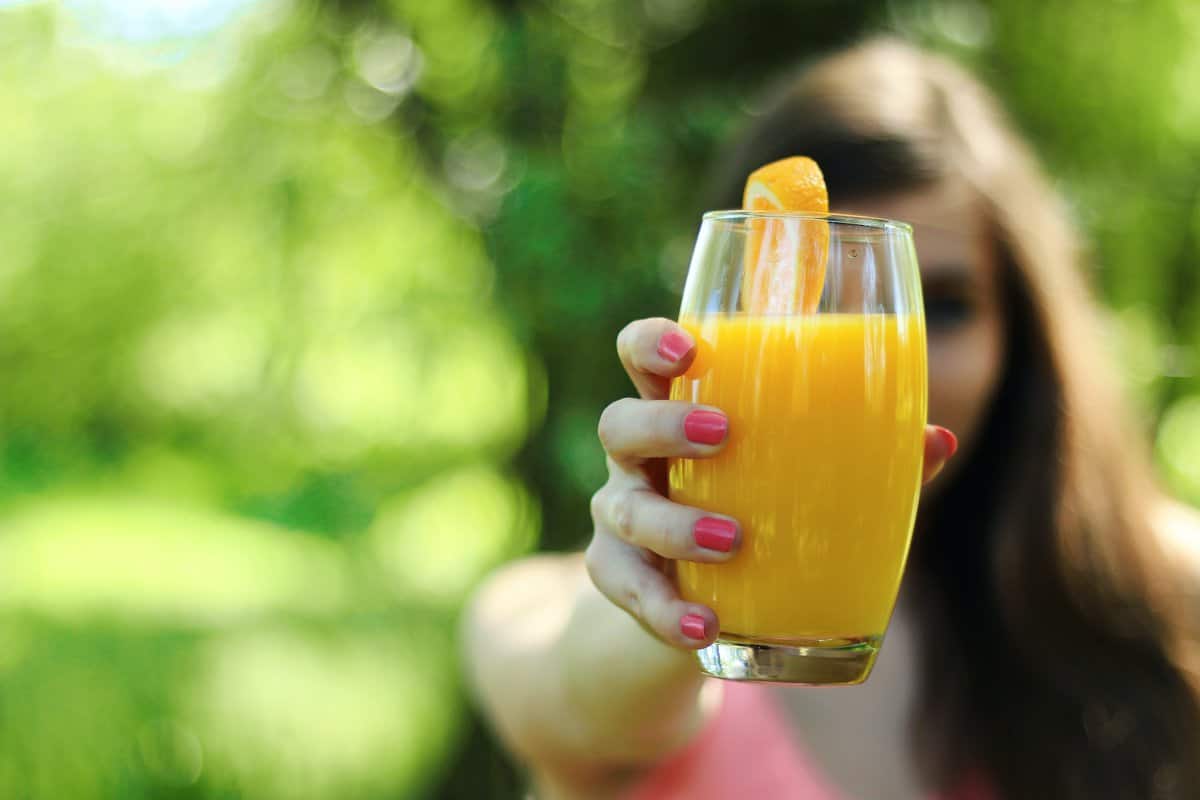 Orange, Mango and Banana Smoothie Popsicles - Woman Holding Glass of Juice