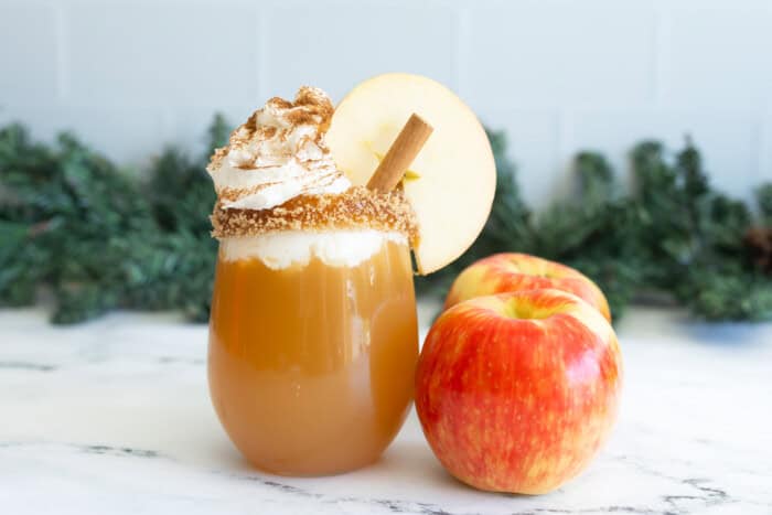 Apple cider mocktail decorated with apples and cinnamon.