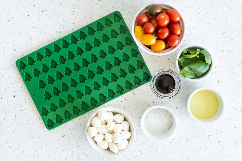 Utensils and ingredients in bowls needed for a mozzarella and tomato recipe