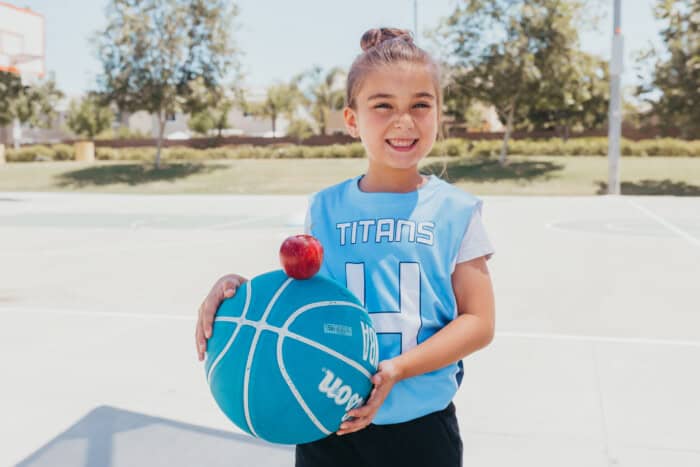 A little girl holding a basketball and an apple
