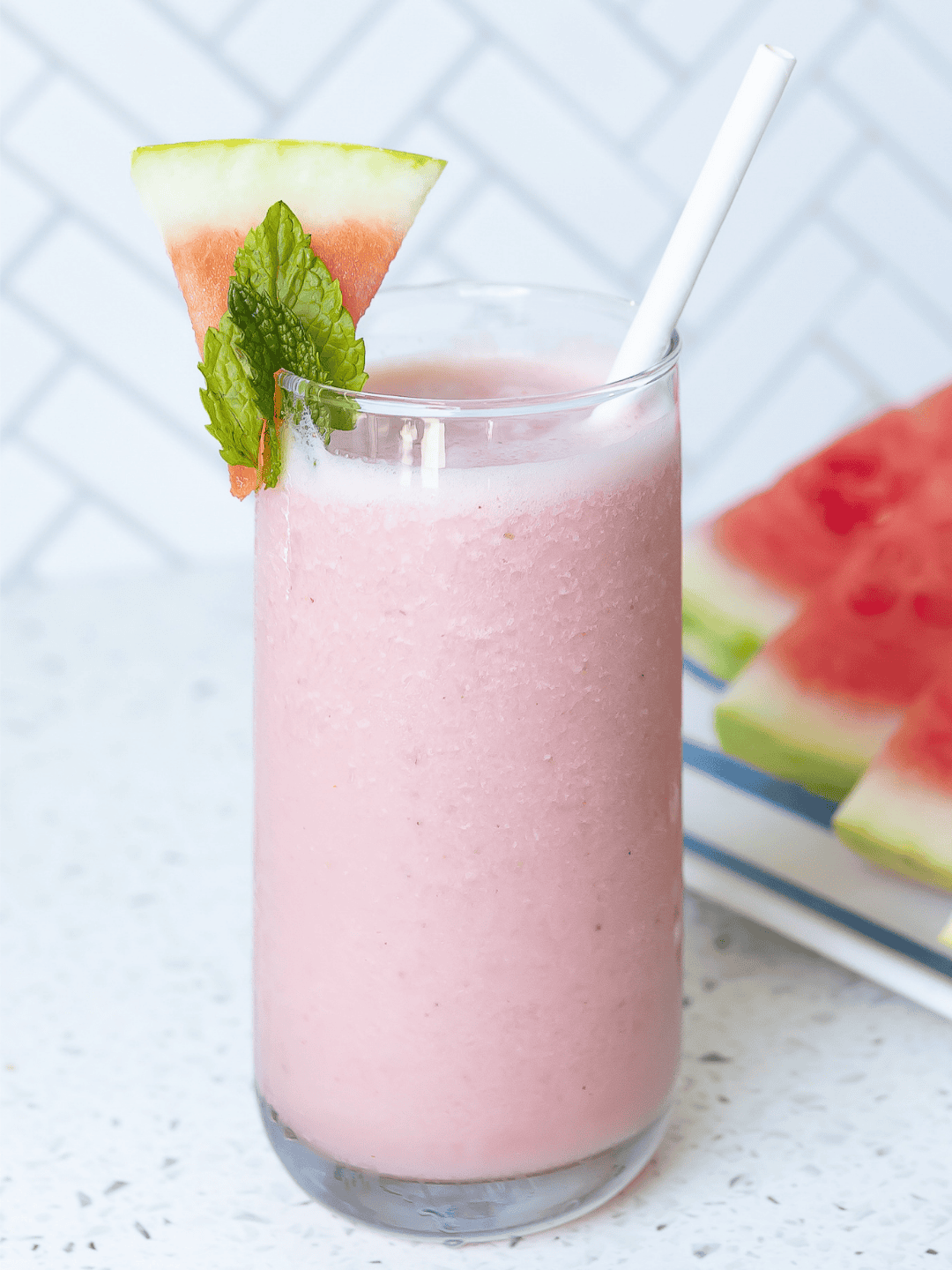 Fruit smoothie in jar with pink straw and watermelon wedge.