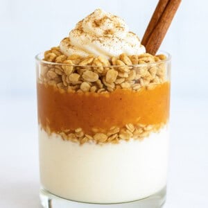 Pumpkin parfait made with protein yogurt, pumpkin puree and granola layered in a glass for a light Thanksgiving dessert.