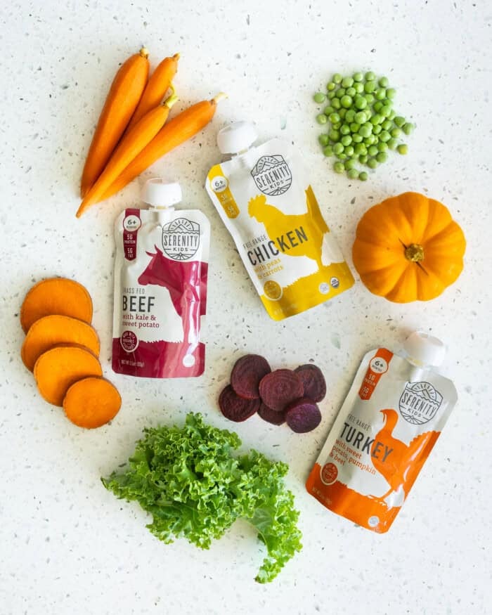 Serenity Kids baby food pouches with turkey, chicken and beef flavors surrounded by holiday vegetables like pumpkin, sweet potato, peas, carrots, kale and beets.