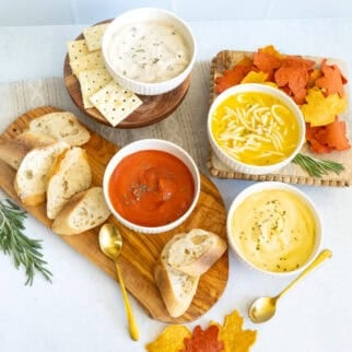Thanksgiving soup bar with tomato soup, creamy chicken soup and noodle soup served with bread, crackers and fall shaped chips.