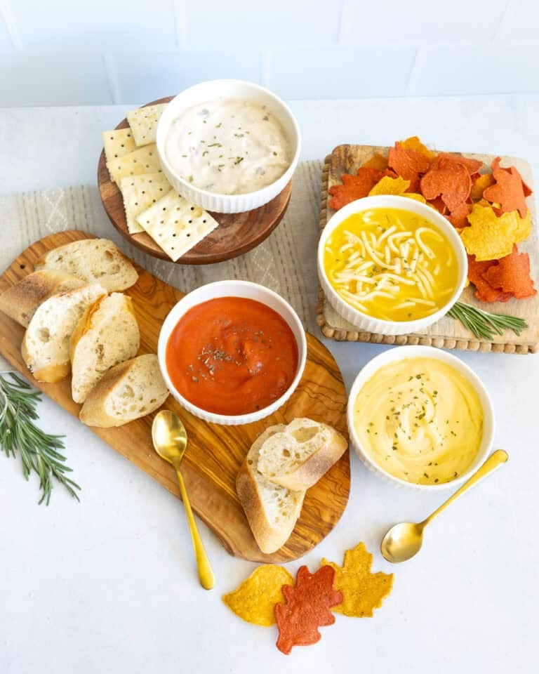 Thanksgiving soup bar with tomato soup, creamy chicken soup and noodle soup served with bread, crackers and fall shaped chips.