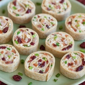 turkey and cranberry pinwheels with bacon and green onions on a soft green plate.
