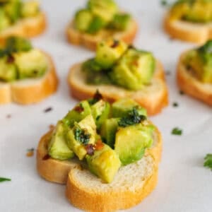 Easy avocado chimichurri bruschetta made with fresh avocado chunks and herbs served on toasted bread slices.