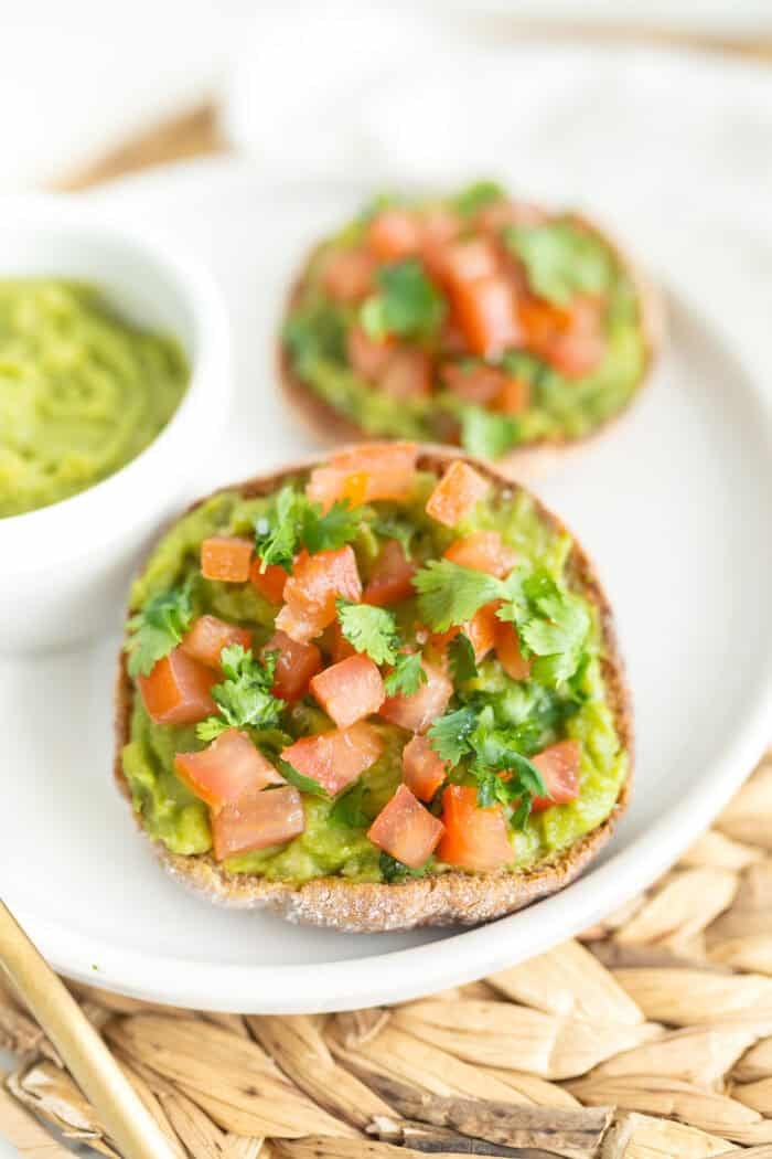 Close up of avocado breakfast English muffin with fresh tomato and cilantro topping