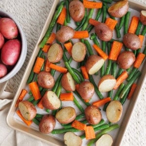 Roasted baby potatoes with green beans and carrots on a sheet pan, ready to bake as an easy vegetable side dish