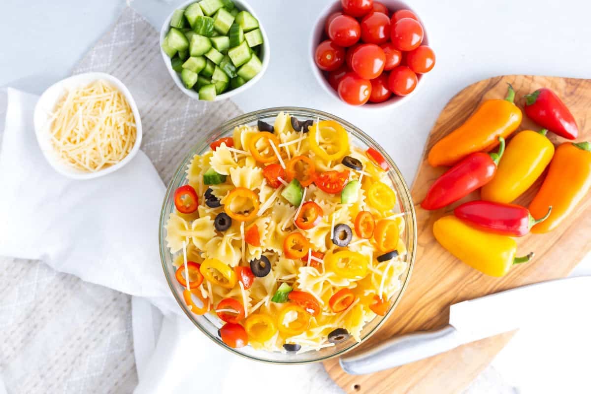Rainbow Italian pasta salad with bowtie pasta, mini sweet peppers, cherry tomatoes, cucumbers, olives, and shredded cheese